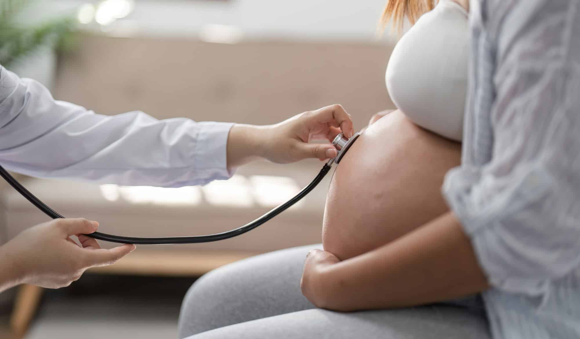 Pregnant Woman Receiving Prenatal Checkup from Doctor with Stethoscope in Modern Medical Clinic